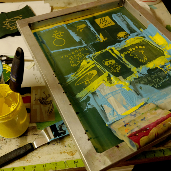 Printing table and screen with yellow and light blue ink.